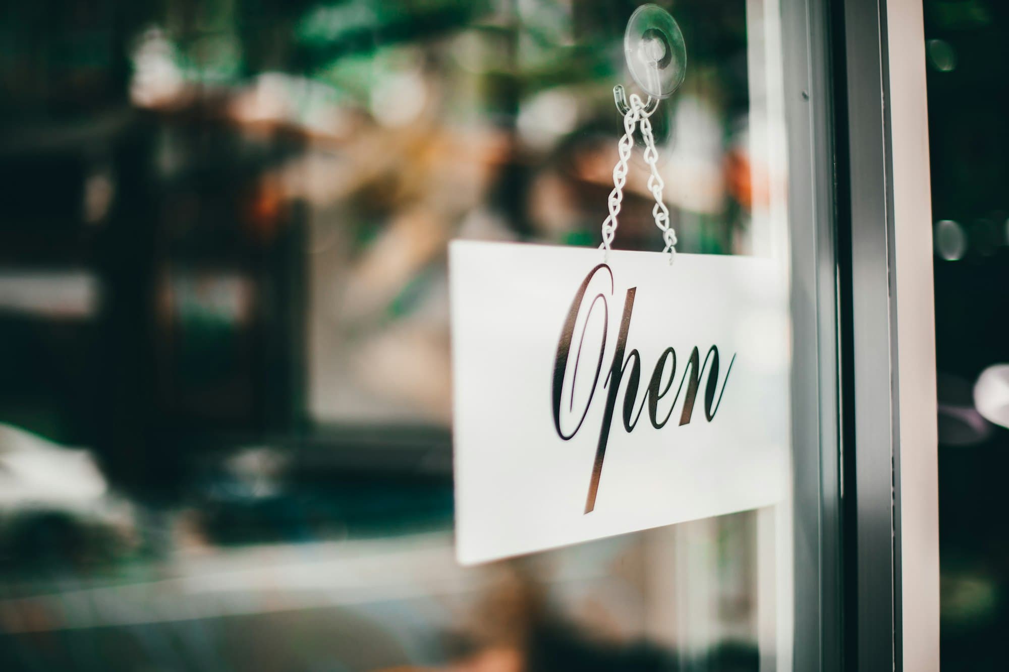 An Open sign hanging in the glass door of a small shop.